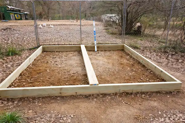 Guide to Making Duck Ponds: Backyard Pond Ideas for Ducks 6 Wooden frame base prepared for building a backyard duck pond, showing leveled ground and foundation setup inside a fenced area